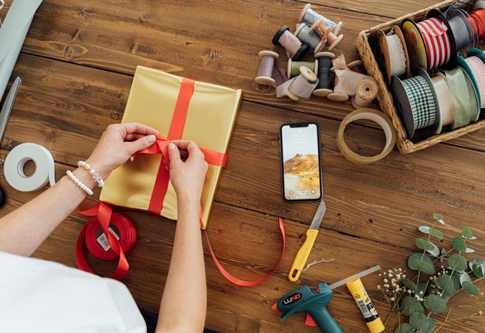 Packtisch mit Geschenkboxen, Seidenpapier und Schleifen (Illustrationsfoto)
